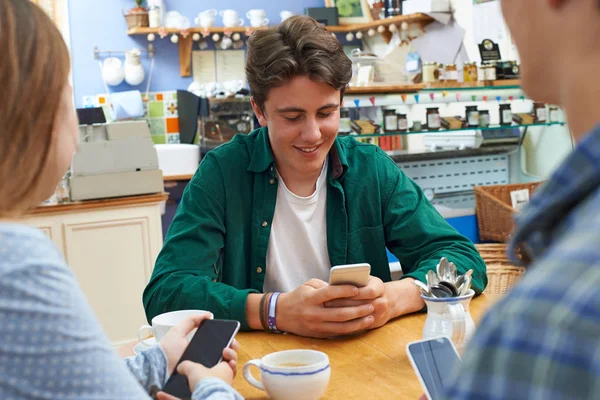 Gruppo di amici adolescenti incontro nel caffè e utilizzando i telefoni cellulari — Foto Stock