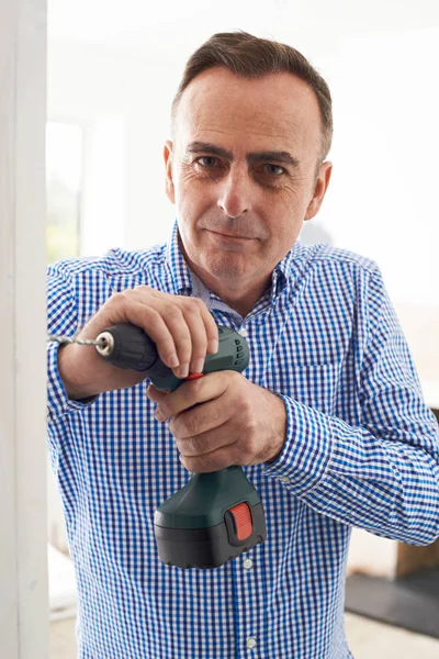 Mann setzt Elektrobohrer bei Haussanierung ein — Stockfoto
