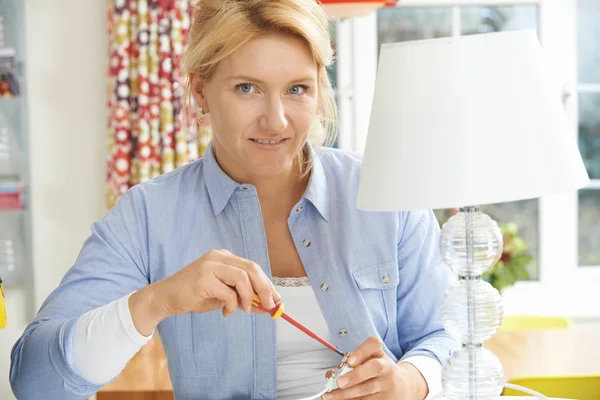 Žena doma zapojení elektrické zásuvky na lampu — Stock fotografie