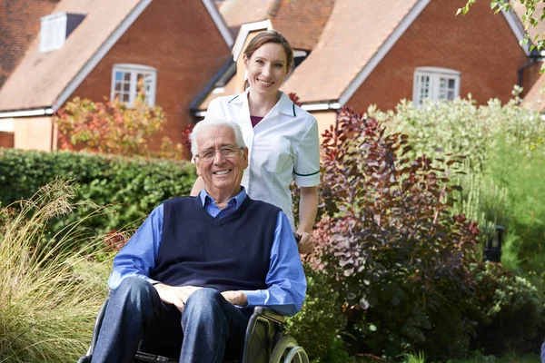 Carer Pushing Senior Man In Wheelchair — Stock Photo, Image