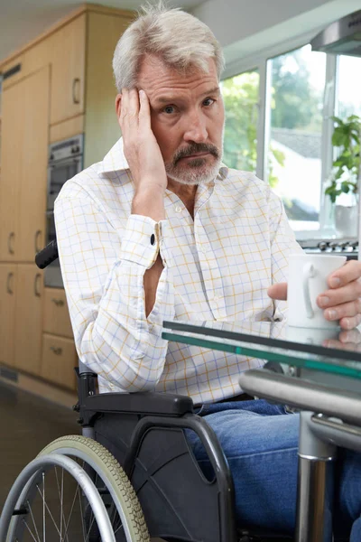 Депрессивный человек сидит в инвалидной коляске дома — стоковое фото