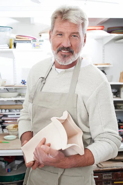 Портрет пожилого человека, держащего вазу в керамической мастерской — стоковое фото