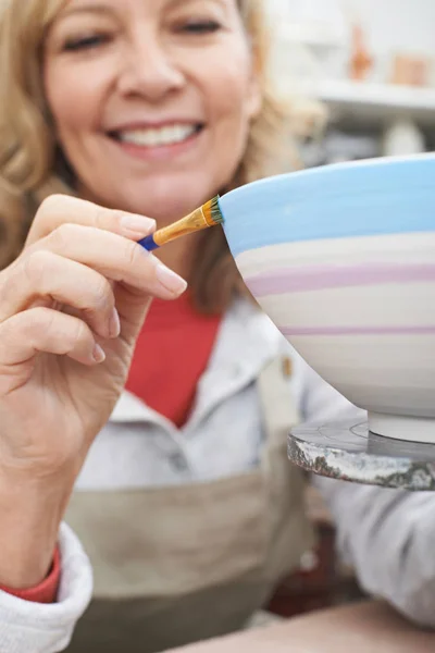 Oudere vrouw versieren Bowl In aardewerk klasse — Stockfoto