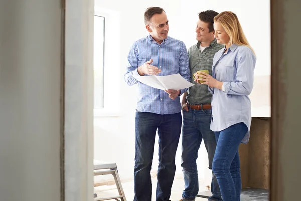 Paar trifft sich mit Architekt oder Bauunternehmer in renovierter Immobilie — Stockfoto