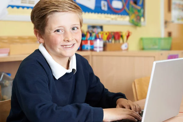 Alumno de la escuela primaria masculina usando el ordenador portátil en la clase de computadora — Foto de Stock