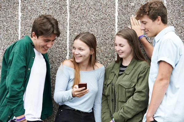 Группа подростков просматривает текстовое сообщение на мобильном телефоне — стоковое фото