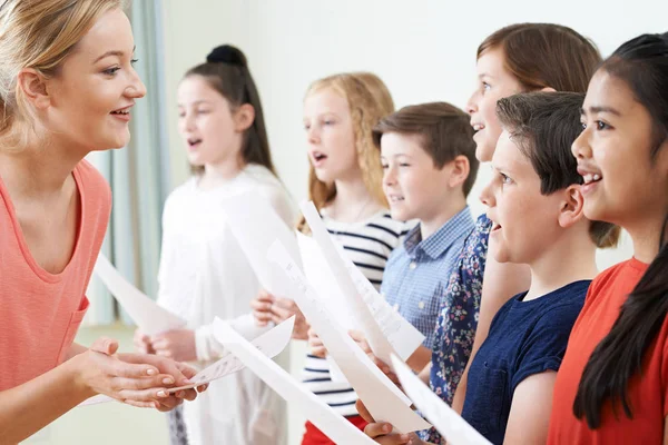 Детей в школьном хоре поощряет учитель — стоковое фото