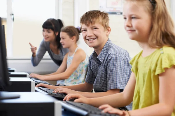 Ученик начальной школы в компьютерном классе с учителем — стоковое фото