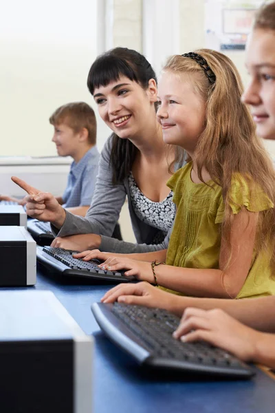 Ученица начальной школы в компьютерном классе с учителем — стоковое фото