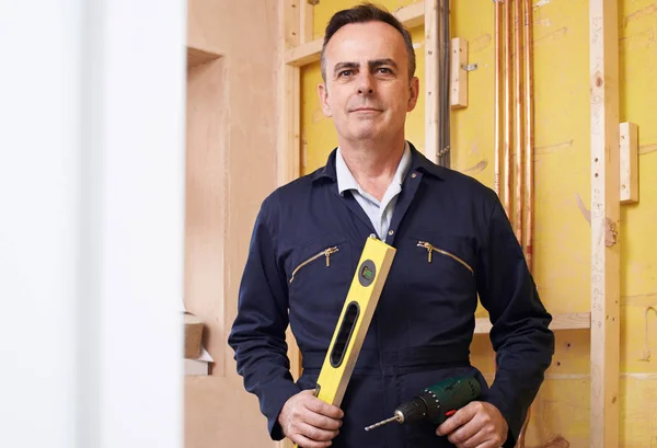 Retrato de constructor masculino con nivel de espíritu y taladro eléctrico — Foto de Stock