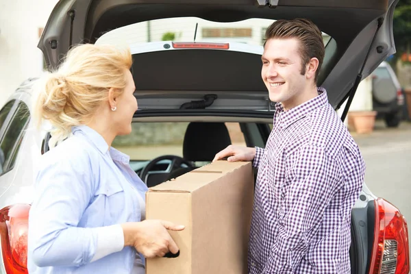 Par lossning nya TV från bilen stammen — Stockfoto