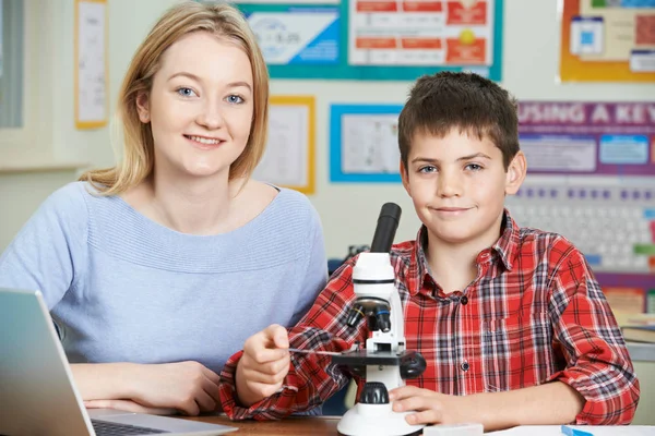 Insegnante con studente maschio utilizzando il microscopio nella classe di scienze — Foto Stock