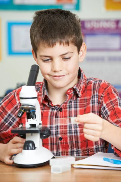 男性生徒が理科の授業で顕微鏡を用いた — ストック写真