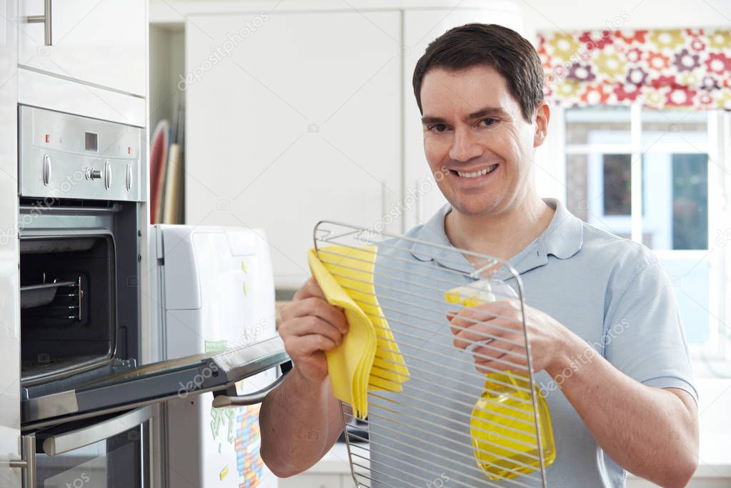Man Cleaning Domestic Oven In Kitchen