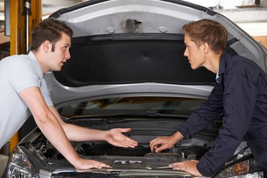 Mekanik, çırakların motoru tamir etmesine yardım ediyor
