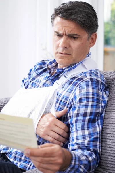 Mature Man Reading Letter About Injury — Stock Photo, Image