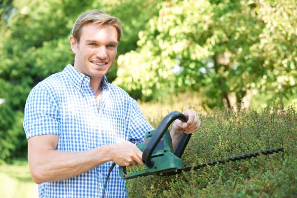 Man Snijden tuin heg met elektrische trimmer — Stockfoto