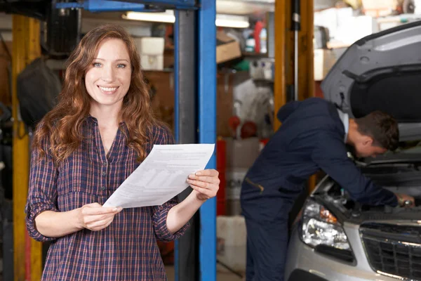 Cliente feminino na oficina de reparação automática satisfeito com Bill para carro — Fotografia de Stock