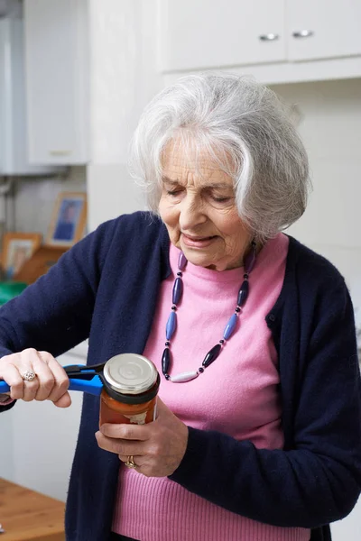 Mujer mayor quitando la tapa del tarro con ayuda de cocina — Foto de Stock