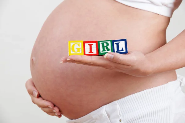 Embarazada mujer celebración de madera bloques ortografía chica — Foto de Stock