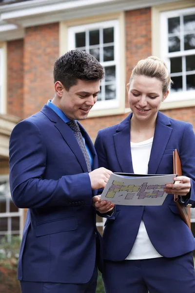 Inmobiliaria masculina y femenina de pie fuera de la propiedad residencial — Foto de Stock