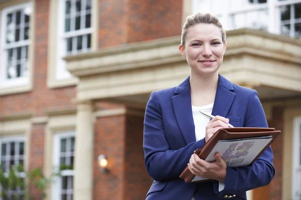 Portret van vrouwelijke makelaar permanent buiten residentieel onroerend goed — Stockfoto