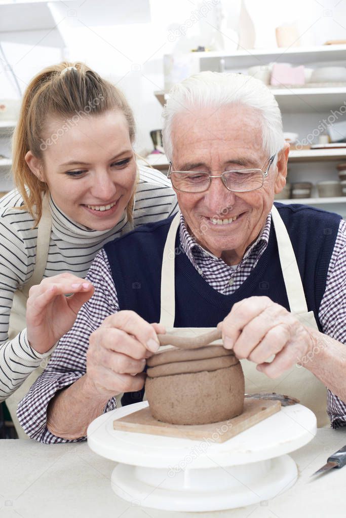 Senior Man With Teacher In Pottery Class