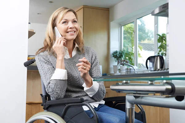 Mulher com deficiência em cadeira de rodas fazendo chamada no celular em casa — Fotografia de Stock