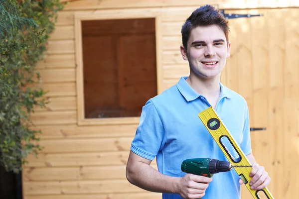 Handwerker steht mit Werkzeug vor Gartenhaus — Stockfoto