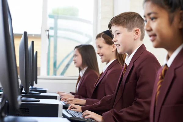 Alunos vestindo uniforme escolar em classe de computador — Fotografia de Stock