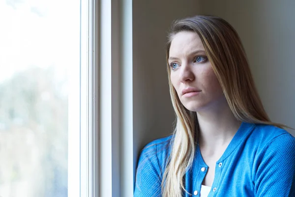 Smutna kobieta cierpi na depresję, patrząc z okna — Zdjęcie stockowe
