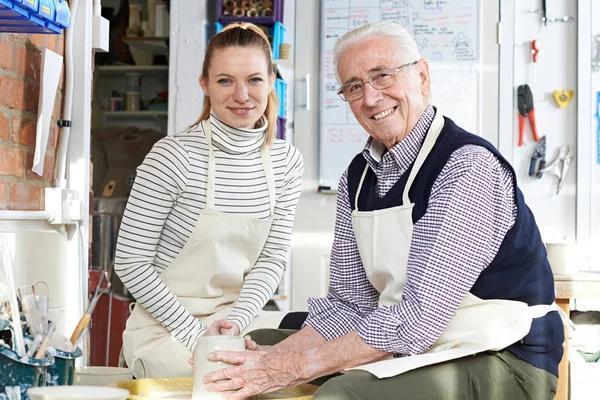 Старший человек с учителем в классе гончарного дела — стоковое фото