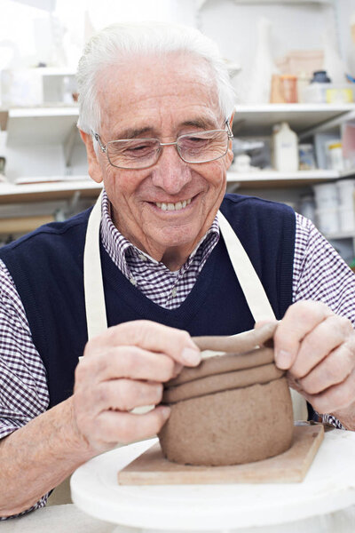 Senior Man Making Coil Pot in Pottery Studio
