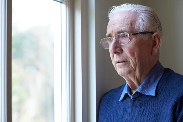 Seniorin mit Depressionen schaut aus dem Fenster — Stockfoto