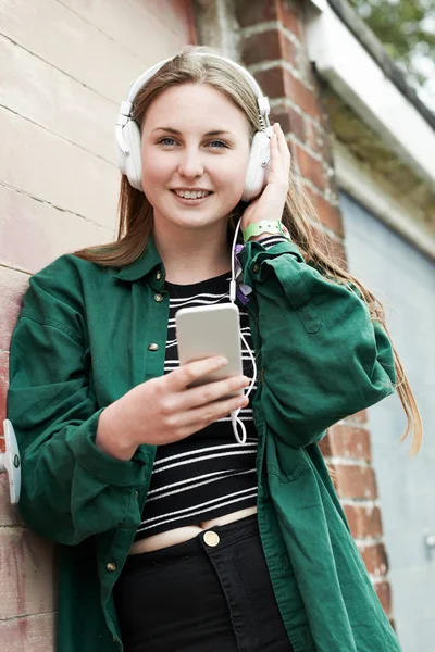 Tonårsflicka bär hörlurar och lyssna på musik i urban — Stockfoto