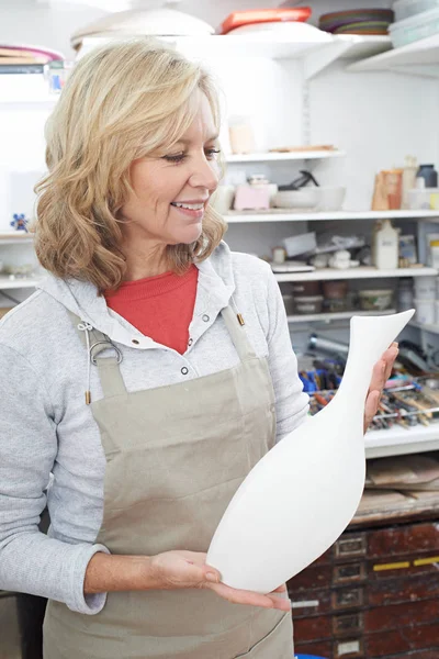 Зріла жінка тримає вазу в студії кераміки — стокове фото