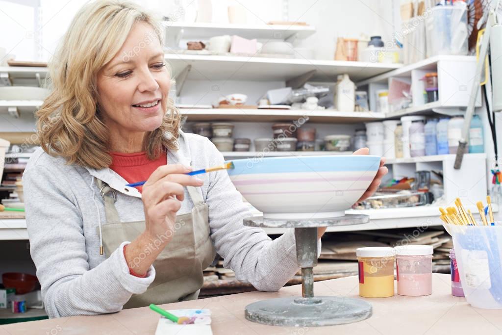 Mature Woman Decorating Bowl In Pottery Class