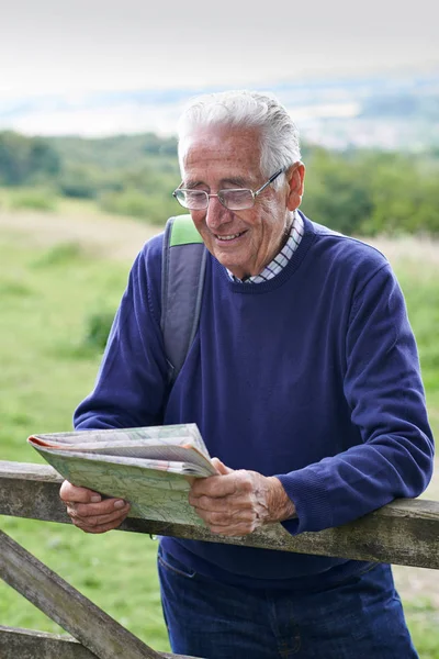 Senior mannen Fotvandring på landsbygden tittar på karta — Stockfoto