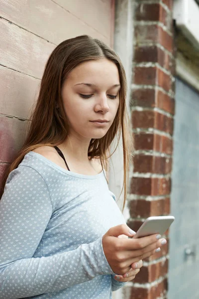 Menina adolescente mensagens de texto no telefone móvel em configuração urbana — Fotografia de Stock