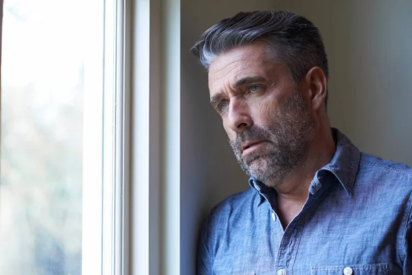 Mature Man Suffering From Depression Looking Out Of Window — Stock Photo, Image