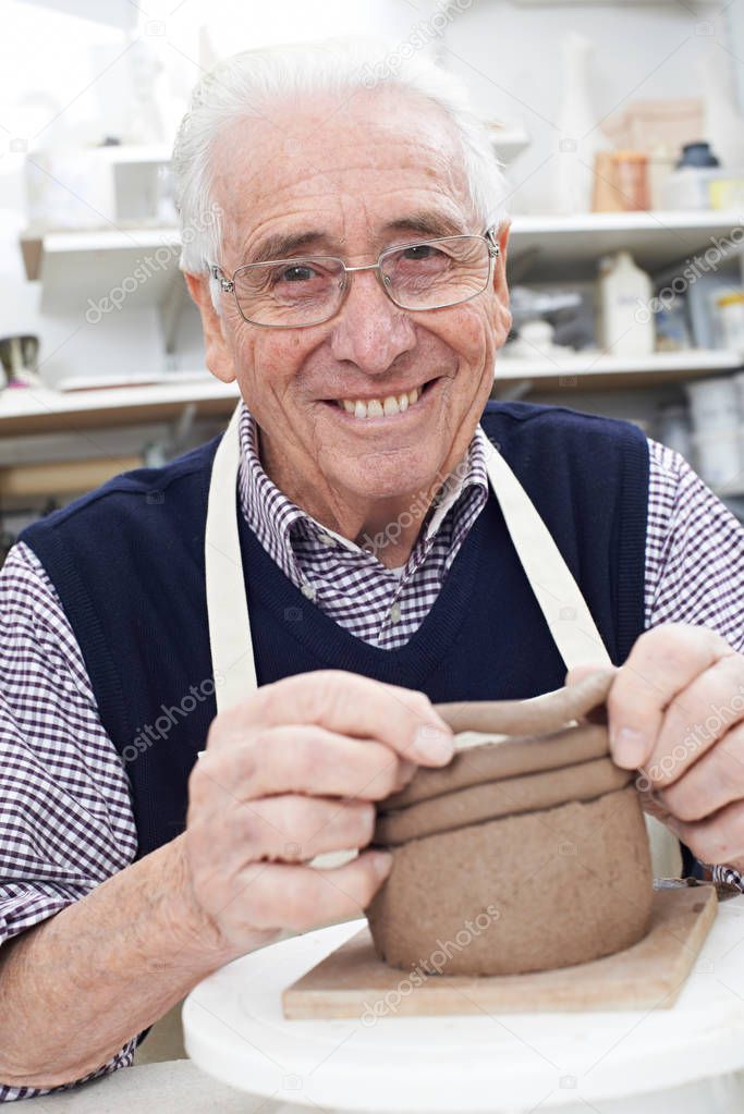Senior Man Making Coil Pot In Pottery Studio