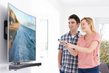 Genç çift evde yeni kavisli ekran televizyonlu