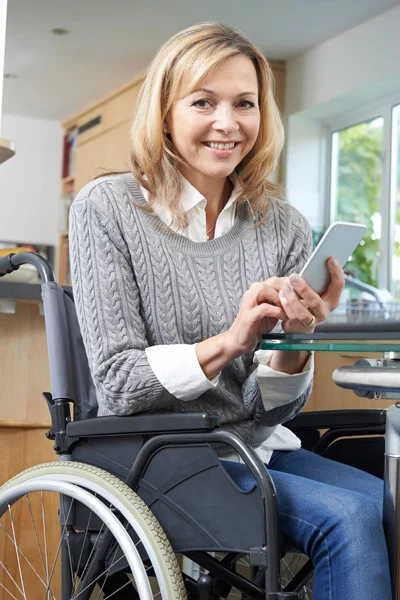 Женщина-инвалид в инвалидной коляске смс на мобильном телефоне дома — стоковое фото