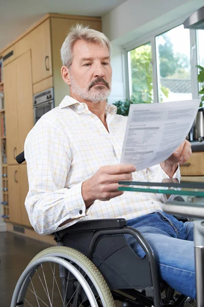 Frustrierter Mann im Rollstuhl zu Hause liest Brief — Stockfoto