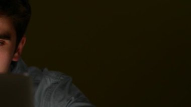 Gece geç saatlerde dizüstü bilgisayar üzerinde çalışan yorgun genç adam