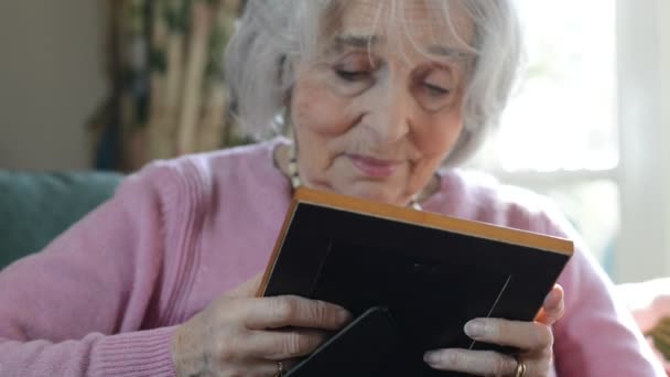 Mujer mayor en casa mirando la foto en el marco — Vídeo de stock