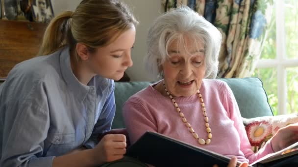 Бабушка смотрит на фотоальбом с взрослой внучкой — стоковое видео