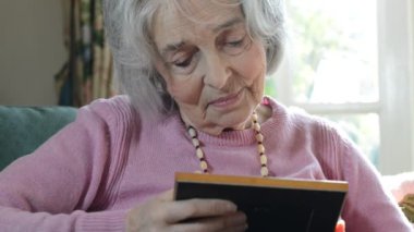 Fotoğraf çerçevesi içinde üst düzey kadın evde bakarak