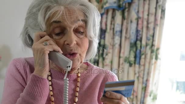 Äldre kvinna ger kreditkortsuppgifter på telefonen — Stockvideo