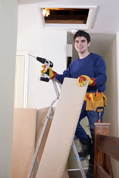 Dělník montážní desky na podlahu podkroví domu — Stock fotografie